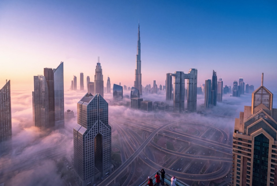 Sisli bir sabahta bulutların üzerinde yükselen Burj Khalifa ve gökdelenler